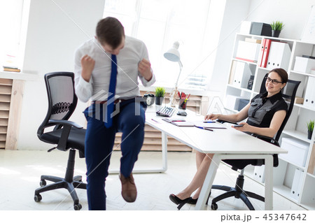 A young girl sitting in the office at the computer table. Next to her is a young man. A young girl sitting in the office at the computer table. Next to her is a young man. 45347642