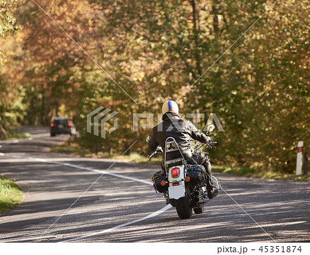 Biker in black leather outfit driving modern powerful motorcycle along sunny road on summer day. Biker in black leather outfit driving modern powerful motorcycle along sunny road on summer day. 45351874
