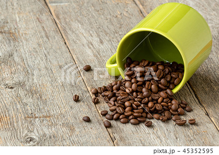 Green cup with scattered coffee beans Green cup with scattered coffee beans 45352595