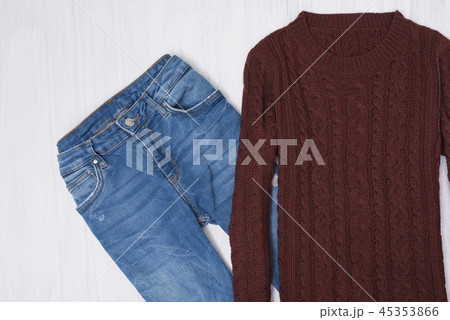 Knitted sweater and jeans on wooden background 45353866
