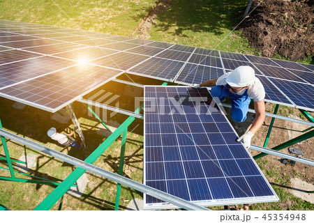 Mounting solar batteries on green metallic carcass by professional workers. Mounting solar batteries on green metallic carcass by professional workers. 45354948