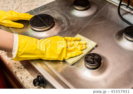 Woman cleaning the stove in the kitchen.  45357931