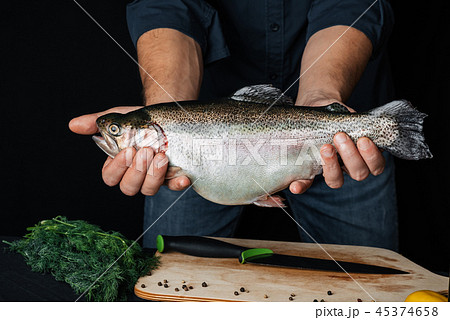 trout in hands of a man on background of kitchen. Big fresh fish with chef 45374658
