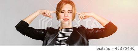 The young girl closed her eyes and put her index fingers to her head. Portrait of a young girl in a 45375440