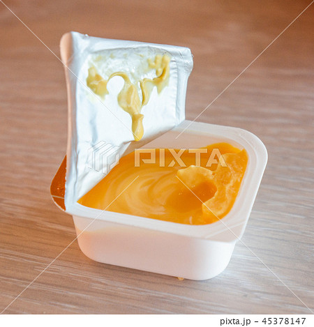 Cheese sauce in plastic cap on wood table 45378147