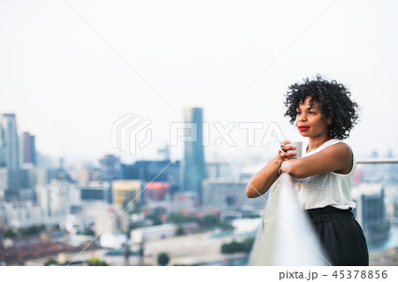 A portrait of a woman standing on a terrace, holding a cup of coffee. A portrait of a woman standing on a terrace, holding a cup of coffee. 45378856
