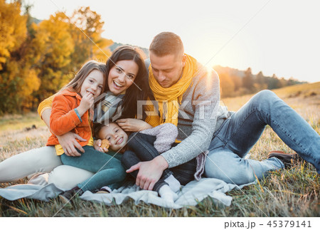 A portrait of young family with two small children in autumn nature at sunset. A portrait of young family with two small children in autumn nature at sunset. 45379141