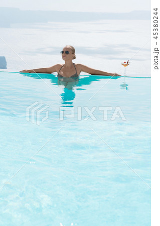 Young woman relaxing in the pool with a gorgeous view on Santorini. 45380244