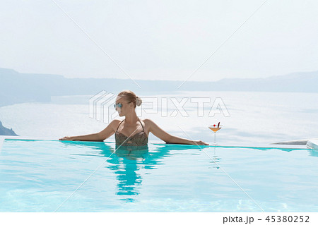 Young woman relaxing in the pool with a gorgeous view on Santorini. Young woman relaxing in the pool with a gorgeous view on Santorini. 45380252