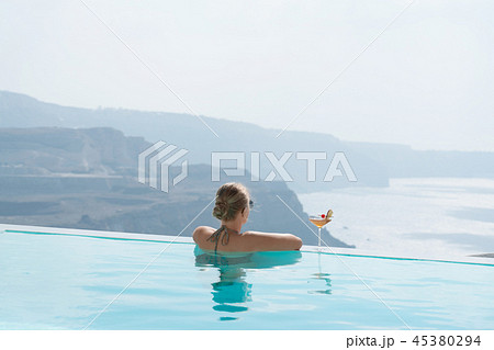 Young woman relaxing in the pool with a gorgeous view on Santorini. 45380294