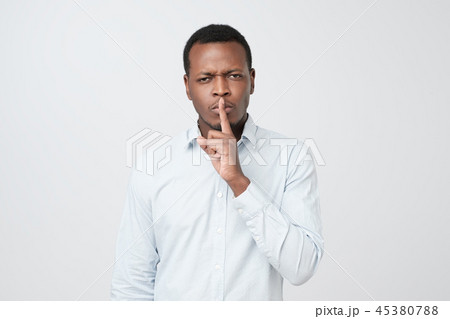 Serious african male keeps index finger on lips Serious african male keeps index finger on lips 45380788