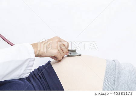 仰向けに寝た妊婦のお腹を聴診器で診察する女医の手元のアップ 妊娠 診察 臨月 検査 産婦人科 女医イの写真素材
