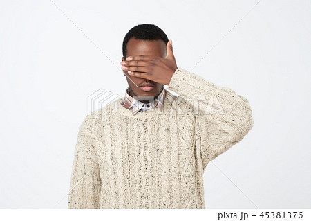 African man in sweater covering his face with hand 45381376