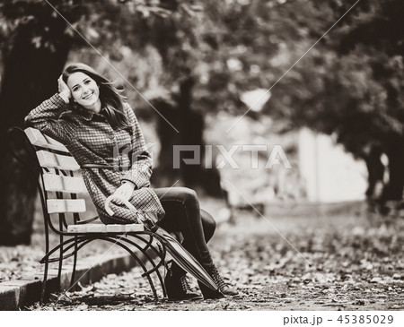 Style girl sitting at bench in autumn park. 45385029