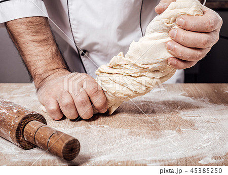 male chef kneads the dough 45385250