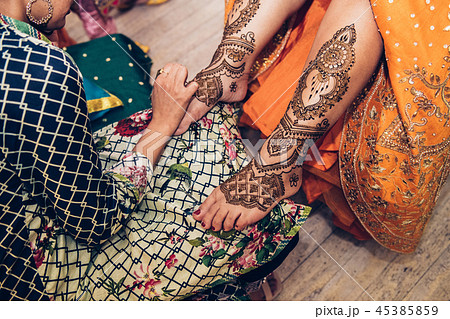 applying traditional Mehndi henna on female leg 45385859