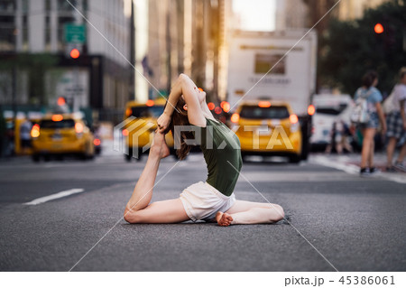 Woman doing yoga pose on city street 45386061