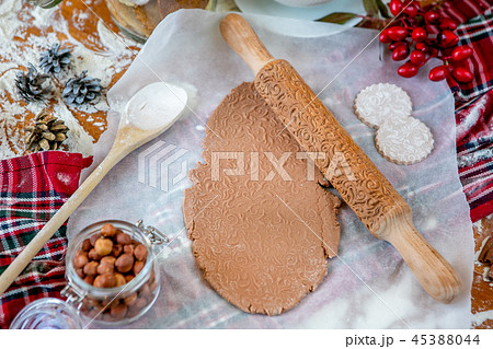 Rolling pin with a pattern on a wooden decorated table covered with baked flour. Rolled dough with a 45388044