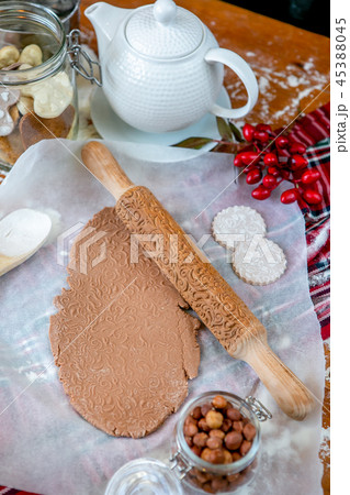 Rolling pin with a pattern on a wooden decorated table covered with baked flour. Rolled dough with a 45388045