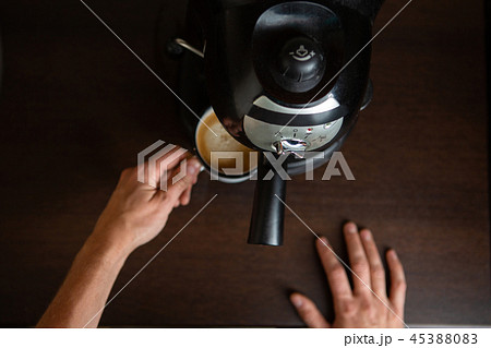 Photo of coffee maker, hands of man pouring coffee in mug Photo of coffee maker, hands of man pouring coffee in mug 45388083