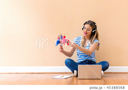 Young woman holding English speaking country flags with laptop 45388568
