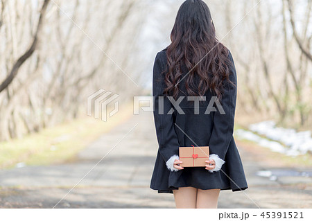 後ろ手にプレゼントボックスを持つ若い女性 45391521