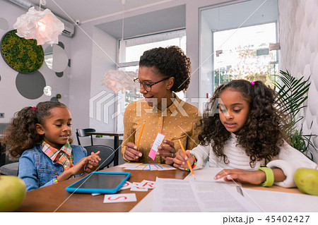 Curly dark-haired cute girls listening attentively to their teacher 45402427