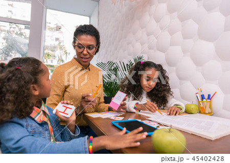 Attentive pleasant nursery teacher telling cute preschoolers about letters 45402428