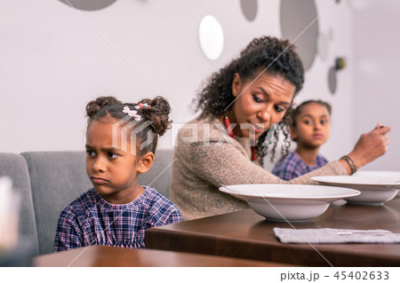 Cute dark-eyed daughter feeling emotional having lunch with mom Cute dark-eyed daughter feeling emotional having lunch with mom 45402633