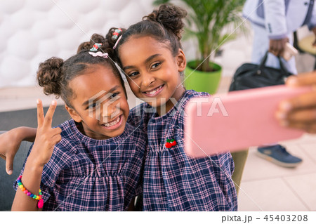 Modern beaming children making selfie while sitting in cafeteria 45403208