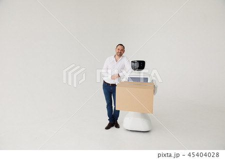 Modern Robotic Technologies. A man communicates with a robot, with cardboard box in hand. 45404028