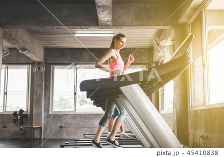 Woman running on treadmills doing cardio training Woman running on treadmills doing cardio training 45410838