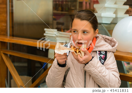 The girl eats a Belgian waffle on the street 45411831