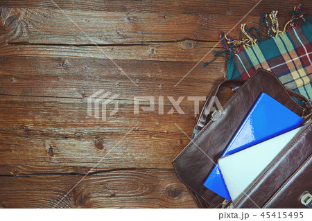 A leather bag with a laptop is lying on a wooden 45415495