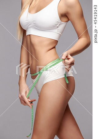 Portrait of beautiful young woman measuring her lfigure size with tape measure. Portrait of beautiful young woman measuring her lfigure size with tape measure. 45419143