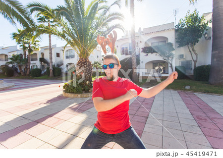 Holidays and people concept - funny man in christmas hat dancing outdoors Holidays and people concept - funny man in christmas hat dancing outdoors 45419471