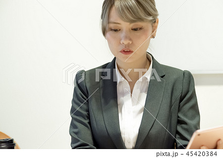 真面目に仕事する20代のOL。パソコン・タブレット・スマホ・書類・パスポート。真剣に考える。悩む。 45420384