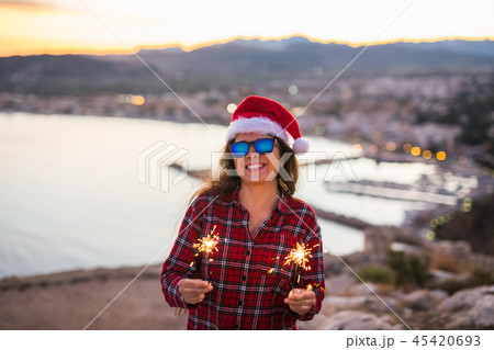 Holiday, Christmas and people concept - Young happy woman in Santa hat over beautiful landscape with 45420693