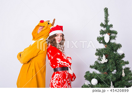 Holiday, humor, people concept - Happy young woman in santa claus hat and man in carnival costume of Holiday, humor, people concept - Happy young woman in santa claus hat and man in carnival costume of 45420899