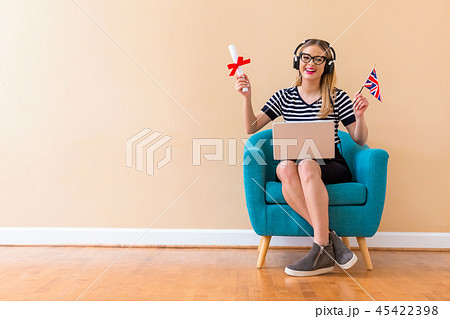 Young woman holding a diploma and UK flag with her laptop Young woman holding a diploma and UK flag with her laptop 45422398