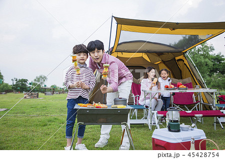 Family having picnic outdoors. Parents with two children relax in the park. Concept of happy family relations and carefree leisure time. 217 45428754