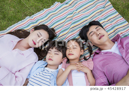 Family having picnic outdoors. Parents with two children relax in the park. Concept of happy family relations and carefree leisure time. 152 45428917