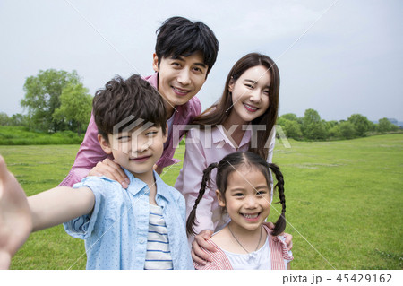 Family having picnic outdoors. Parents with two children relax in the park. Concept of happy family relations and carefree leisure time. 005 45429162