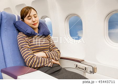 飛行機 機内 旅行 女性 寝るの写真素材