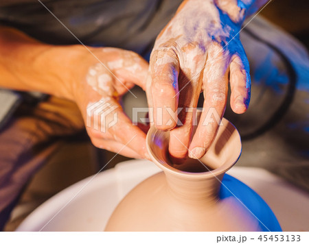 Artist operates hands, which gently creating correctly shaped handmade from clay. Traditional 45453133