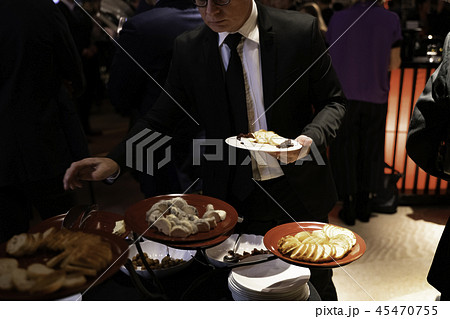 パーティーシーン 立食パーティーの取り皿に盛り付ける人の写真素材