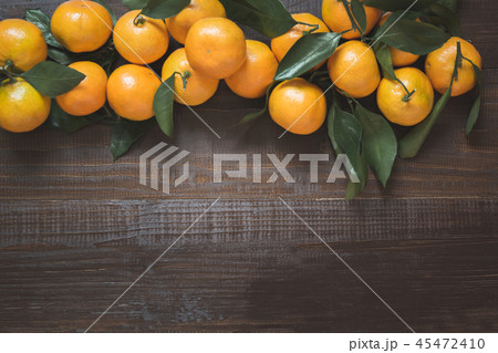 Fresh mandarins with leaves on wooden board.  45472410