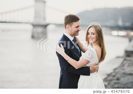 Elegant stylish happy blonde bride and gorgeous groom on the background of a beautiful river Elegant stylish happy blonde bride and gorgeous groom on the background of a beautiful river 45479370