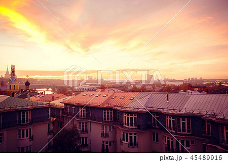 Clouds of beautiful color against the roofs of houses. Sunset pink red orange. 45489916