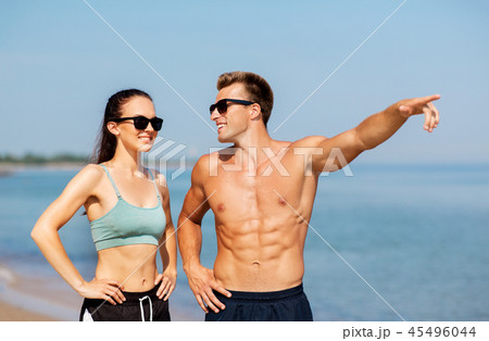 happy couple in sports clothes and shades on beach 45496044